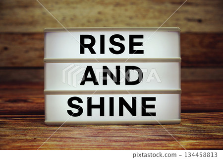 Lightbox with text "Rise And Shine" on wooden background Lightbox with text "Rise And Shine" on wooden background 134458813