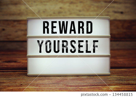Lightbox with text "Reward Yourself" on wooden background 134458815