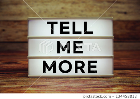 Lightbox with text "Tell Me More" on wooden background 134458818
