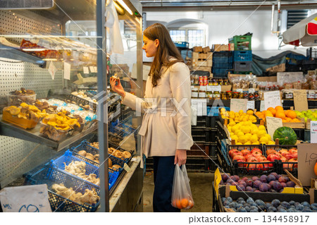 Woman choosing desserts at a bakery stand in a farmers market. Urban food shopping experience. 134458917