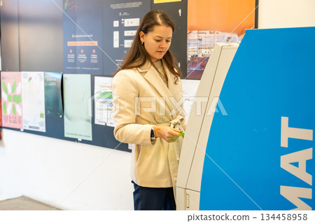 Woman using ATM machine in public indoor location. Managing personal finances and daily tasks. 134458958
