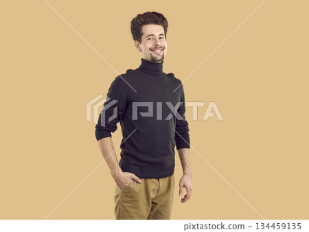 Portrait of happy confident brunet guy in black turtleneck on beige background looking at camera. Portrait of happy confident brunet guy in black turtleneck on beige background looking at camera. 134459135