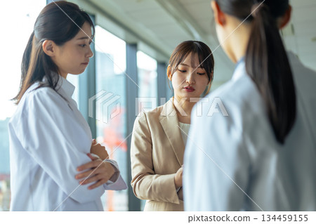 一位身穿白大褂的女士與一位醫藥代表進行嚴肅的諮詢場景。 134459155
