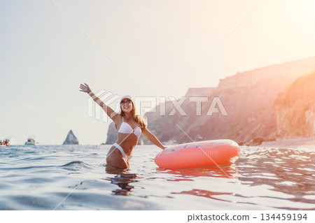 Woman, ocean, swimming woman in white bikini enjoying a summer vacation at the beach with an inflatable donut. Woman, ocean, swimming woman in white bikini enjoying a summer vacation at the beach with an inflatable donut. 134459194