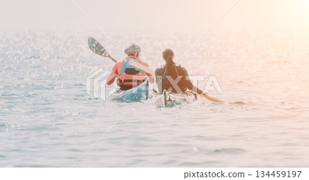 Kayaking Couple Ocean Sunset - Two people kayaking in the ocean at sunset. Kayaking Couple Ocean Sunset - Two people kayaking in the ocean at sunset. 134459197