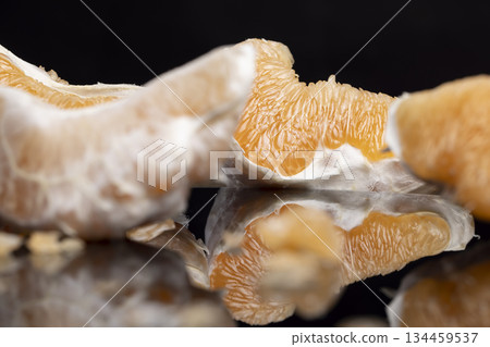 half of an orange citrus on a black mirror, ripe and sweet and juicy citrus is reflected on the mirror, closeup 134459537