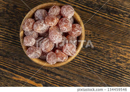 small fruits of fragrant kumquat dried in sugar syrup, food details, round dehydrated kumquat fruit in a wooden bowl 134459546