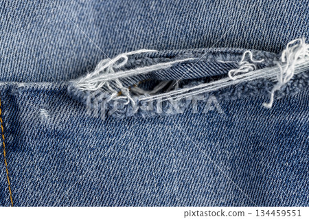 old blue torn jeans from long-term wear, part of blue jeans made of cotton fabric that are frayed and torn from long-term wear and use 134459551