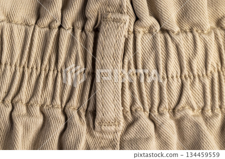 a new beige denim fabric from trousers, details of the beige fabric from which trousers or other clothes are sewn 134459559