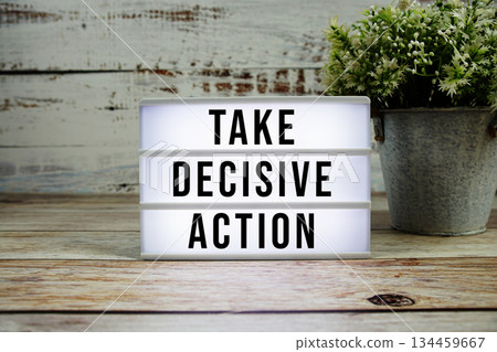 Take Decisive Action text on light box on wooden background 134459667