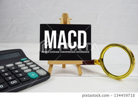 MACD abbreviation of Moving Average Convergence Divergence text with magnifying glass and calculator on wooden background MACD abbreviation of Moving Average Convergence Divergence text with magnifying glass and calculator on wooden background 134459718