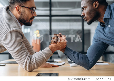 Two office workers are having fun and doing arm wrestling Two office workers are having fun and doing arm wrestling 134459965