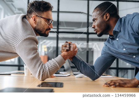 Two office workers are having fun and doing arm wrestling Two office workers are having fun and doing arm wrestling 134459966