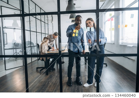 Ideas are on the glass, standing. Professional workers are in the modern office together 134460040