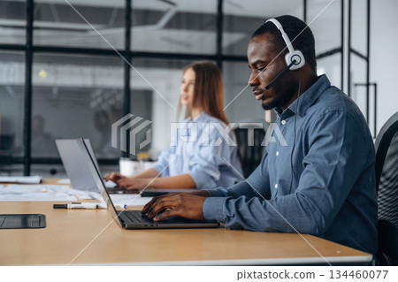 In headphones and with laptops. People are working in the call center In headphones and with laptops. People are working in the call center 134460077