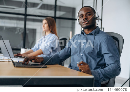 In headphones and with laptops. People are working in the call center In headphones and with laptops. People are working in the call center 134460078