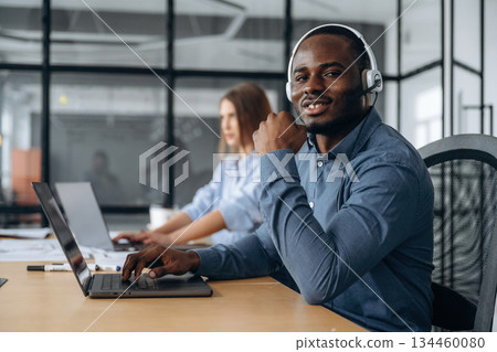 In headphones and with laptops. People are working in the call center In headphones and with laptops. People are working in the call center 134460080