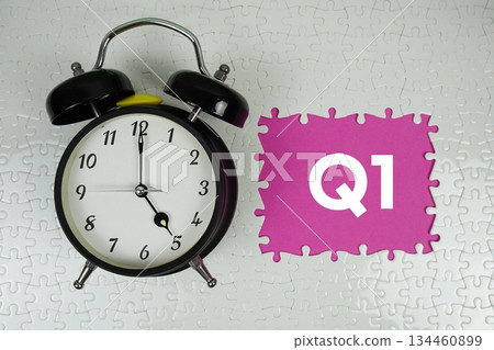 Jigsaw puzzle with a missing piece with "1st Quarter Financial Report" and alarm clock on pink background Jigsaw puzzle with a missing piece with "1st Quarter Financial Report" and alarm clock on pink background 134460899