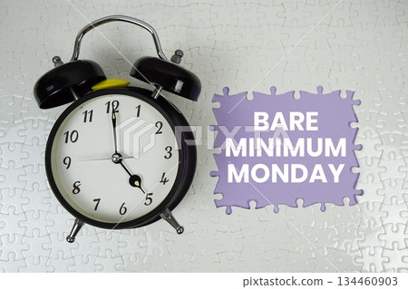 Jigsaw puzzle with a missing piece with "Bare Minimum Monday" and alarm clock on purple background 134460903