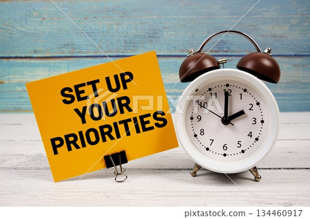 Set Up Your Priorities text written on paper card with alarm clock on wooden background Set Up Your Priorities text written on paper card with alarm clock on wooden background 134460917