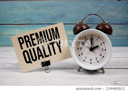 Premium Quality text written on paper card with alarm clock on wooden background Premium Quality text written on paper card with alarm clock on wooden background 134460921