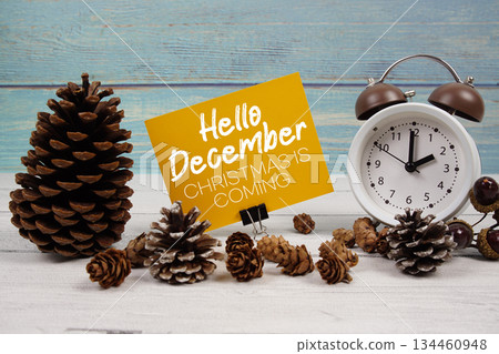 Hello December Christmas Is Coming text written on paper card with alarm clock and pine cones decoration on wooden background Hello December Christmas Is Coming text written on paper card with alarm clock and pine cones decoration on wooden background 134460948