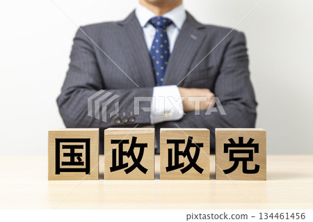 一位商人雙手交叉放在胸前,旁邊立著一塊寫有「國家政黨」字樣的牌子。 一位商人雙手交叉放在胸前,旁邊立著一塊寫有「國家政黨」字樣的牌子。 134461456
