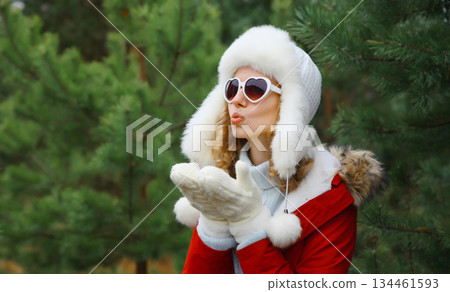 Happy young woman in winter park against Christmas tree, girl in white hat, glasses in snowy forest 134461593