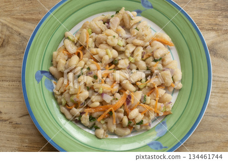 white bean salad with carrots and herbs on green plate close up 134461744