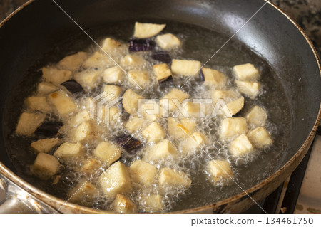eggplant cubes frying in hot oil in pan on stove for cooking eggplant cubes frying in hot oil in pan on stove for cooking 134461750