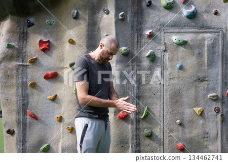 Man Applying Chalk to Hands Before Climbing at Outdoor Bouldering Park 134462741