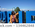 Young woman traveler in yellow jacket posing by the iconic Darjeeling signage with Himalayan mountains background 134462848