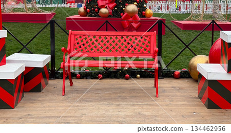 Red bench placed among Christmas decorations in outdoor holiday installation. Festive public space, seasonal decor, winter celebration, urban tradition and cozy Christmas atmosphere Red bench placed among Christmas decorations in outdoor holiday installation. Festive public space, seasonal decor, winter celebration, urban tradition and cozy Christmas atmosphere 134462956