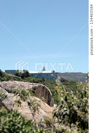House on hill, surrounded vegetation and large rocks. Residential architecture House on hill, surrounded vegetation and large rocks. Residential architecture 134463584