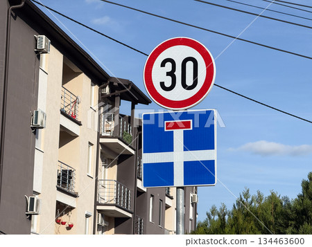 Road speed 30 sign in residential area. Urban safety, slow traffic and calm driving environment for pedestrians and local residents. Road speed 30 sign in residential area. Urban safety, slow traffic and calm driving environment for pedestrians and local residents. 134463600