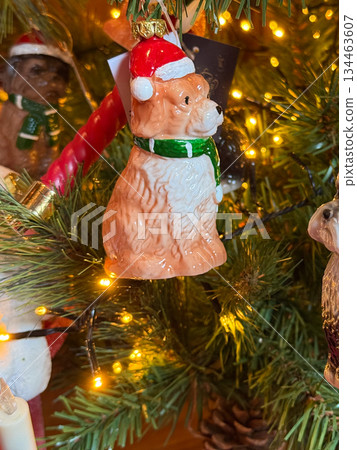 Holiday puppy ornament on a festive Christmas tree. Joyful warmth and seasonal charm in a glowing celebration of winter magic and traditional decor creating emotional connection and cozy holiday 134463607