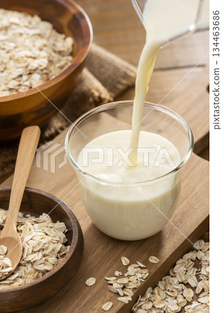 Oat milk and oat ingredients poured into a glass Oat milk and oat ingredients poured into a glass 134463686