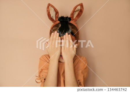 A girl dressed up as a horse hides her face behind her hands. A child in the guise of a pony. New Year of the horse according to the Eastern calendar A girl dressed up as a horse hides her face behind her hands. A child in the guise of a pony. New Year of the horse according to the Eastern calendar 134463742