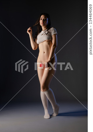 Woman in lingerie elegantly dancing with a rose in a dimly lit studio Woman in lingerie elegantly dancing with a rose in a dimly lit studio 134464069