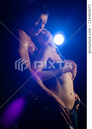 Dancers embrace passionately under a spotlight in a dramatic performance setting 134464071