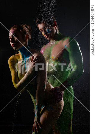 Couple poses with body paint under water spray in a studio setting Couple poses with body paint under water spray in a studio setting 134464072