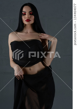 Elegant woman modeling black lingerie with sheer fabric indoors 134464077