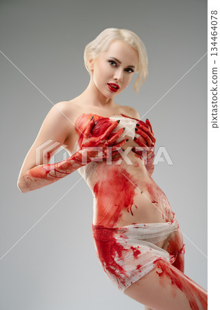 Woman posing in studio with blood bodyart in creative expression Woman posing in studio with blood bodyart in creative expression 134464078
