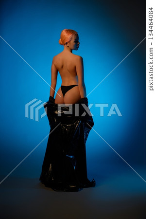 Woman in lingerie poses against a blue background with artistic lighting Woman in lingerie poses against a blue background with artistic lighting 134464084