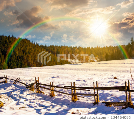 rustic wooden fence through snow covered hill at sunset. beautiful view in winter mountains in evening light. alpine rural landscape near forest. leadership corporate wallpaper under rainbow rustic wooden fence through snow covered hill at sunset. beautiful view in winter mountains in evening light. alpine rural landscape near forest. leadership corporate wallpaper under rainbow 134464095