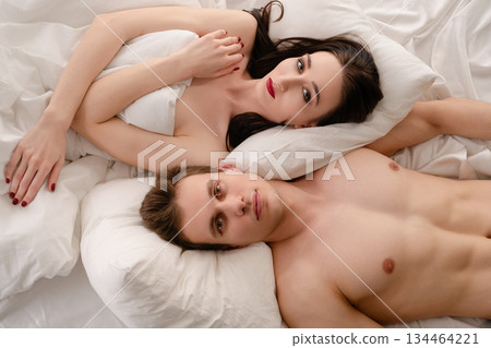 Couple relaxing together on a bed, enjoying a peaceful moment in the morning Couple relaxing together on a bed, enjoying a peaceful moment in the morning 134464221