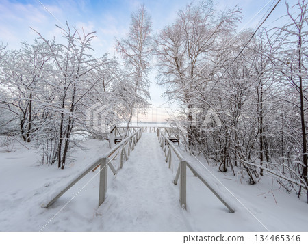 Winter landscape with snow covered trees and pier. Lake covered with thin ice. 134465346