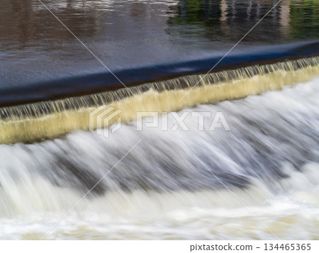 A small flat cascade in a calm river 134465365