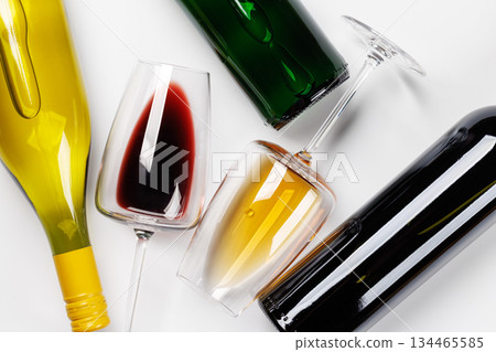 Wine glasses with red and white wine and bottles lying on white background 134465585