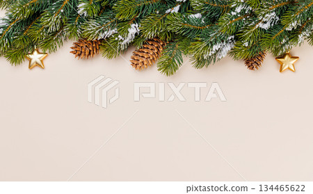 Snowy fir branches with cones on beige background Snowy fir branches with cones on beige background 134465622